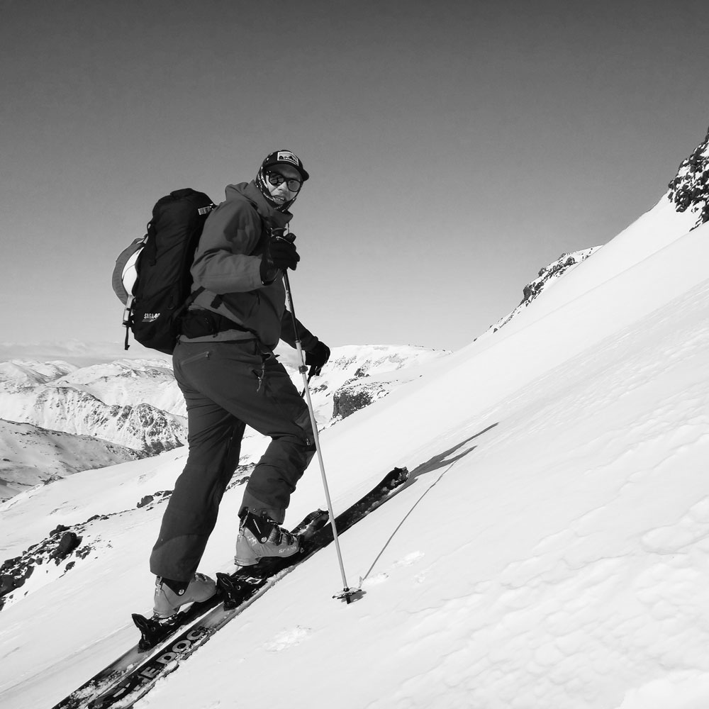 Skinning up a snow covered mountain on skis wearing BAIST ski gloves