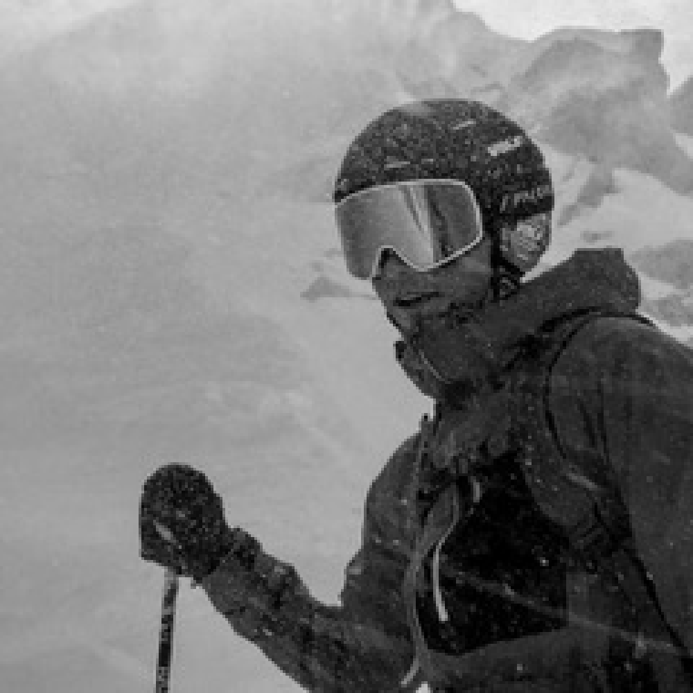 Man wearing a helmet and goggles holding a ski pole